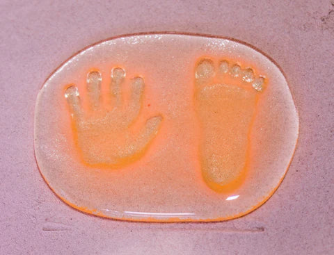 New born baby hand and foot print set into glass.